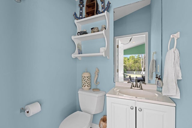 bathroom with toilet, vanity, and vaulted ceiling