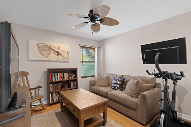 living room featuring ceiling fan, a textured ceiling, and light hardwood / wood-style flooring