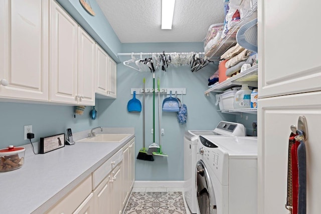 washroom with cabinets, a textured ceiling, sink, light tile patterned floors, and washing machine and clothes dryer