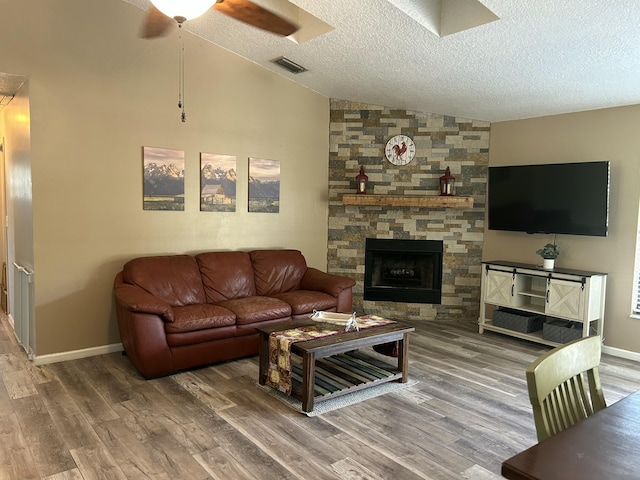 living room featuring hardwood / wood-style floors, lofted ceiling, a fireplace, and a textured ceiling