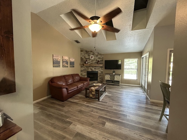 living room with a fireplace, a textured ceiling, ceiling fan, and dark wood-type flooring