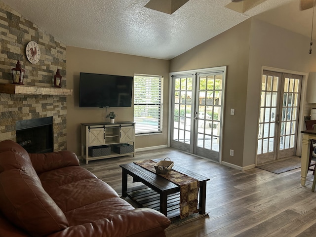 living room featuring a stone fireplace, french doors, vaulted ceiling, and hardwood / wood-style flooring