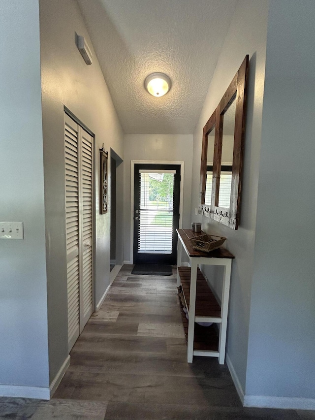 entryway featuring a textured ceiling, dark hardwood / wood-style floors, and lofted ceiling