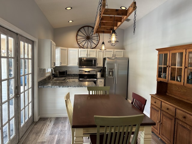 dining room with wood-type flooring, sink, high vaulted ceiling, and french doors