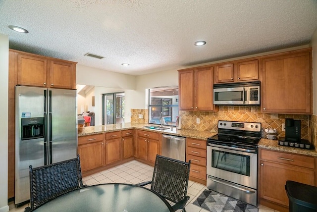 kitchen featuring light stone countertops, sink, a textured ceiling, decorative backsplash, and appliances with stainless steel finishes