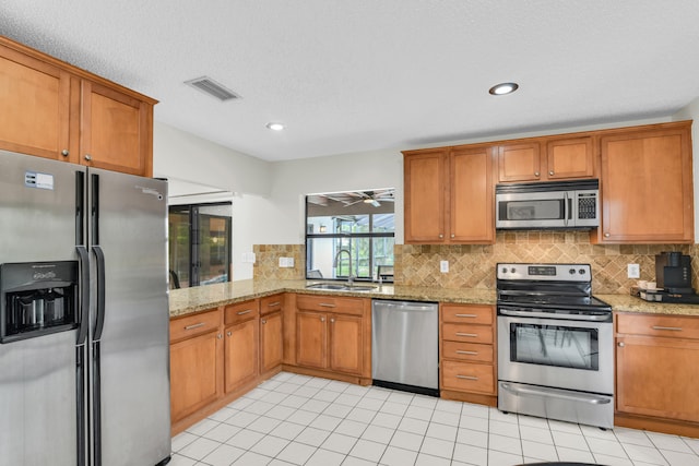 kitchen featuring light stone counters, a sink, visible vents, appliances with stainless steel finishes, and tasteful backsplash