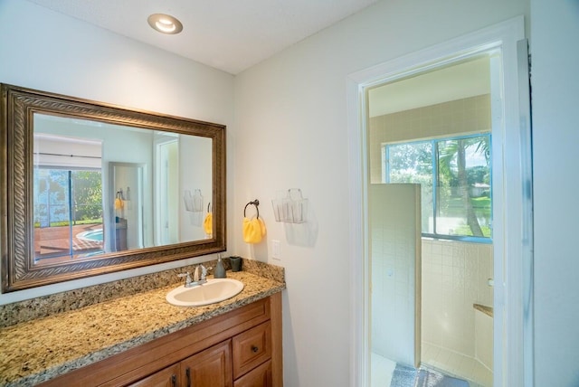 bathroom with a shower, vanity, and a healthy amount of sunlight