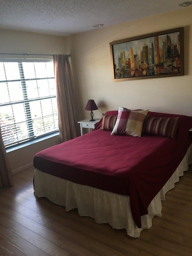 bedroom featuring hardwood / wood-style flooring, a textured ceiling, and multiple windows