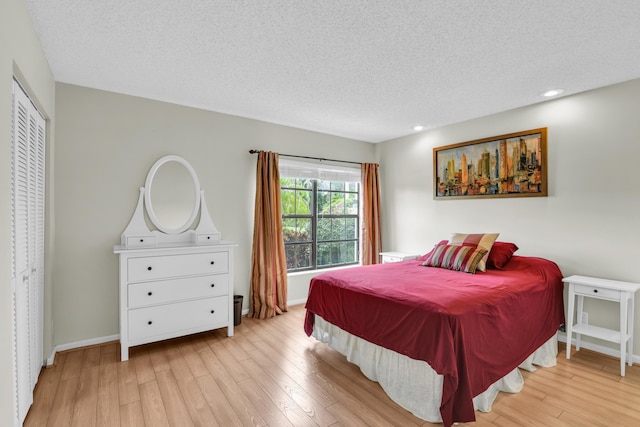 bedroom featuring a textured ceiling, light wood finished floors, and baseboards