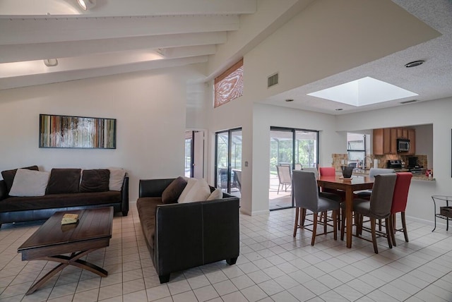 tiled living room with vaulted ceiling with skylight and sink