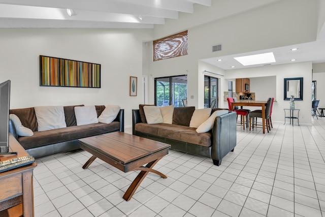 living room with light tile patterned floors, recessed lighting, a skylight, visible vents, and beamed ceiling