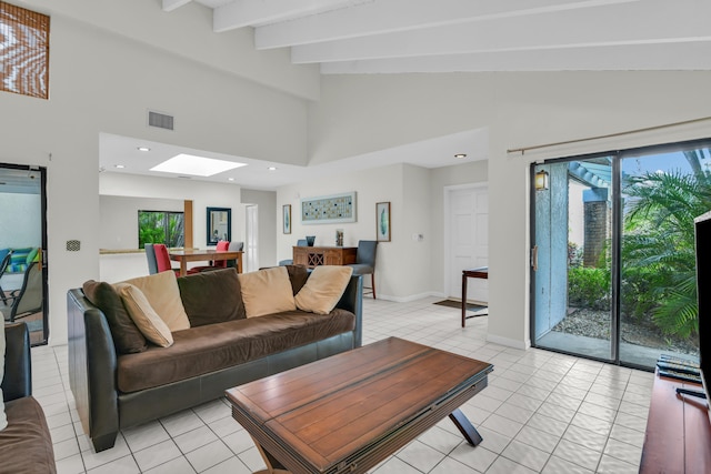 living area featuring light tile patterned floors, a skylight, visible vents, and beam ceiling