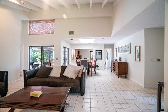 living room featuring beam ceiling, light tile patterned floors, a towering ceiling, and a skylight