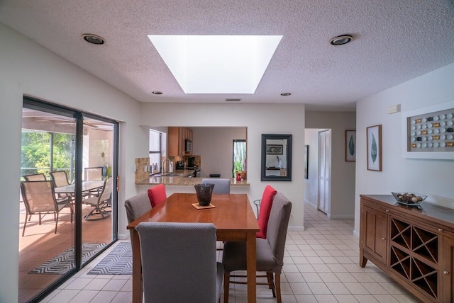 tiled dining area featuring a textured ceiling and a skylight