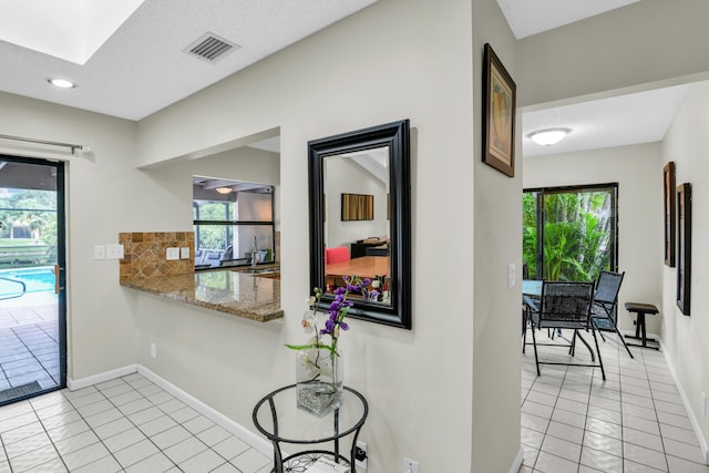 interior space with light tile patterned floors, a textured ceiling, a skylight, visible vents, and baseboards