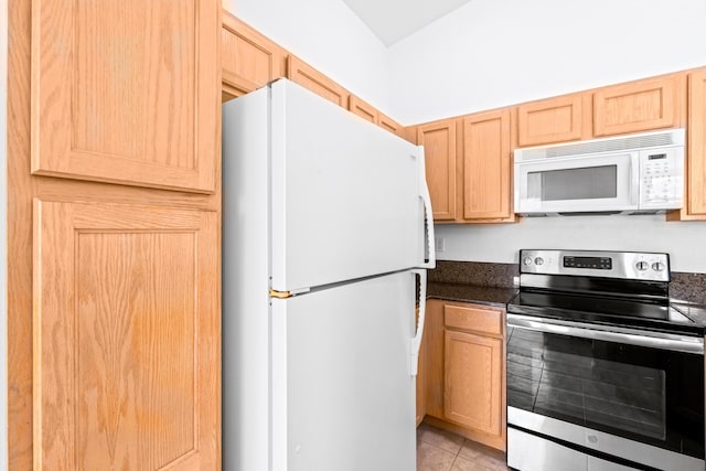 kitchen featuring light tile patterned flooring, dark stone countertops, white appliances, and light brown cabinetry