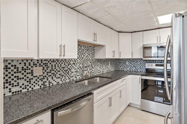 kitchen featuring appliances with stainless steel finishes, white cabinetry, decorative backsplash, sink, and a paneled ceiling