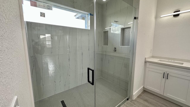 bathroom with a shower with door, vanity, and wood-type flooring