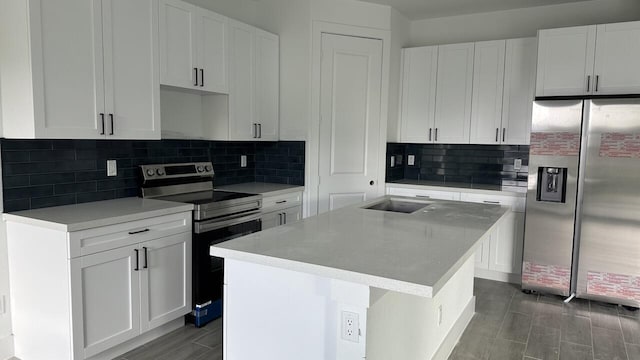 kitchen with a center island, white cabinets, sink, decorative backsplash, and appliances with stainless steel finishes