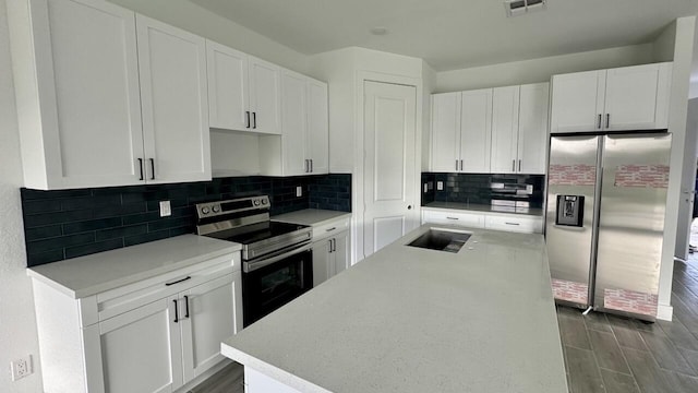 kitchen featuring tasteful backsplash, white cabinetry, a center island, and appliances with stainless steel finishes