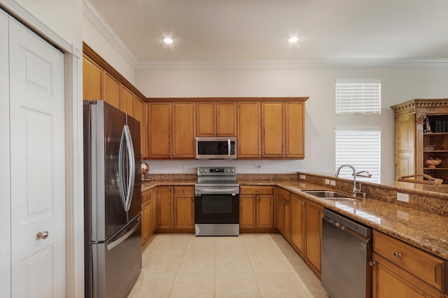 kitchen featuring light stone counters, sink, ornamental molding, and appliances with stainless steel finishes