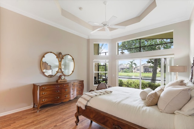 bedroom with a tray ceiling, ceiling fan, ornamental molding, and hardwood / wood-style flooring