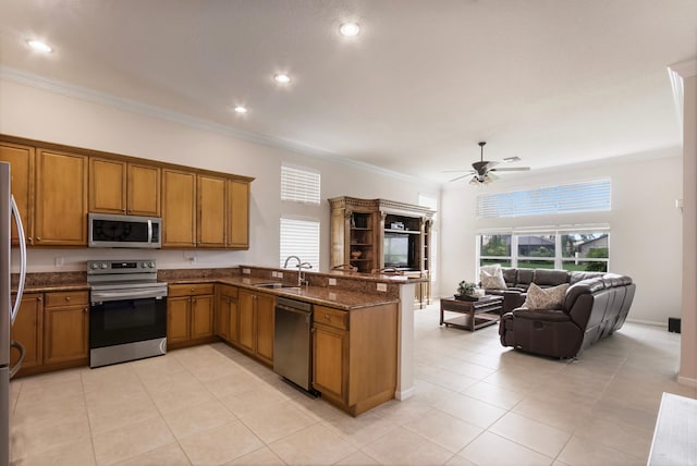 kitchen featuring sink, kitchen peninsula, crown molding, dark stone countertops, and appliances with stainless steel finishes