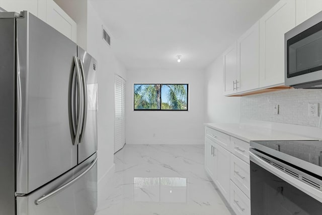 kitchen with white cabinetry, backsplash, and appliances with stainless steel finishes