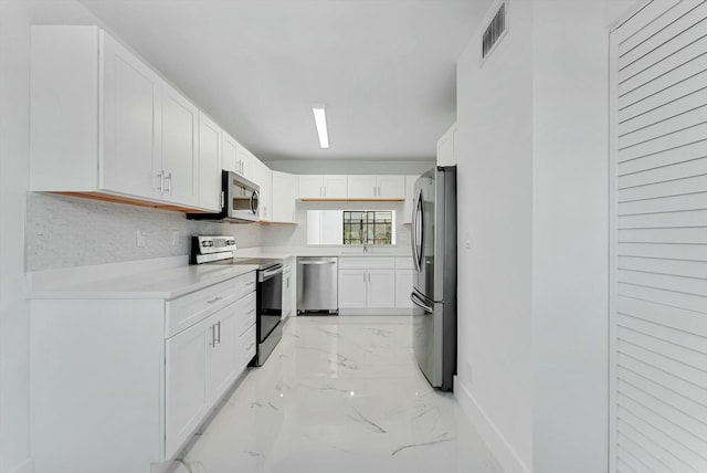 kitchen featuring tasteful backsplash, white cabinetry, and stainless steel appliances