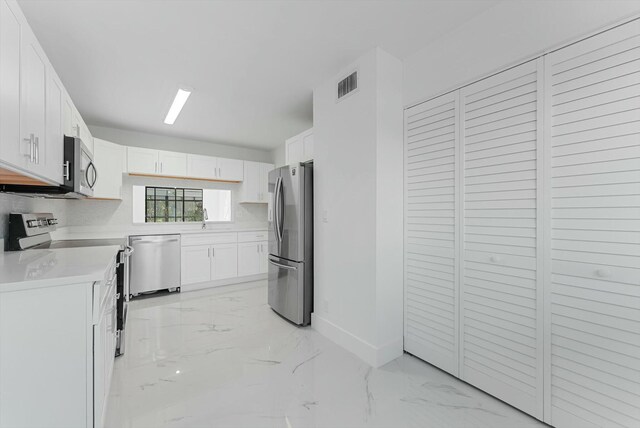 kitchen featuring tasteful backsplash, sink, white cabinets, and appliances with stainless steel finishes