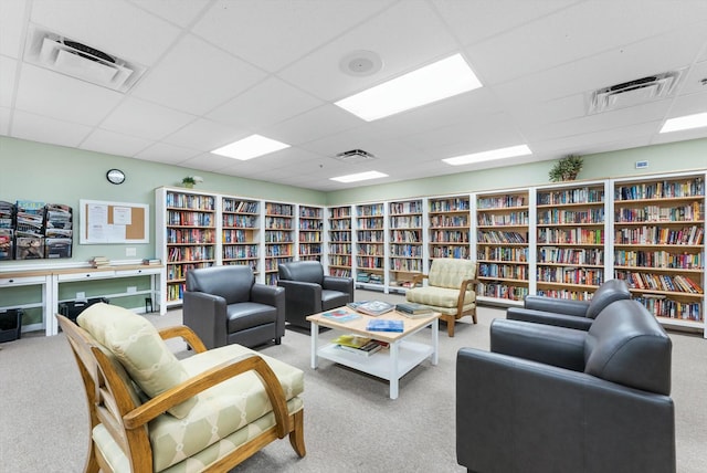 carpeted living room featuring a drop ceiling