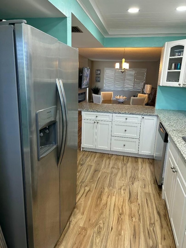 kitchen with kitchen peninsula, hanging light fixtures, white cabinets, and stainless steel appliances