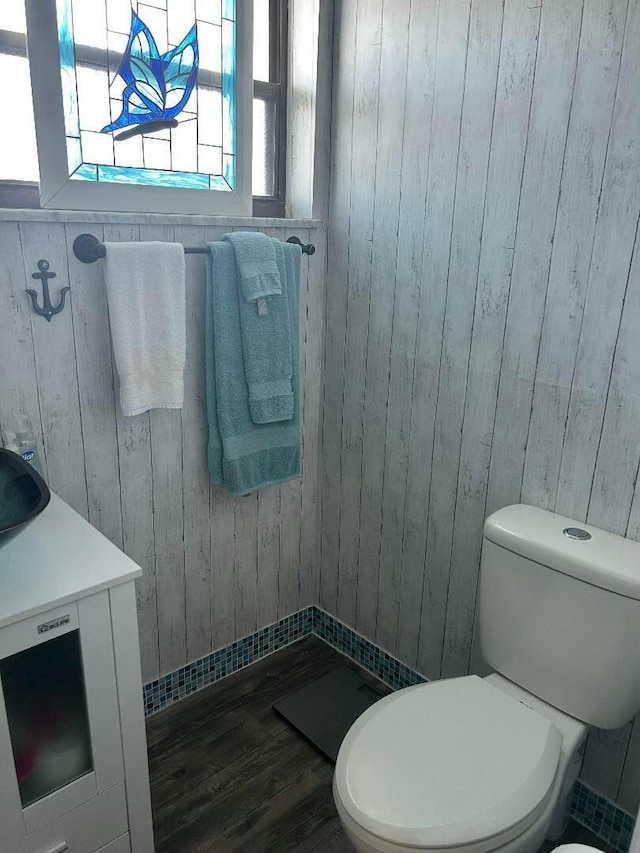 bathroom featuring hardwood / wood-style floors, toilet, and wooden walls