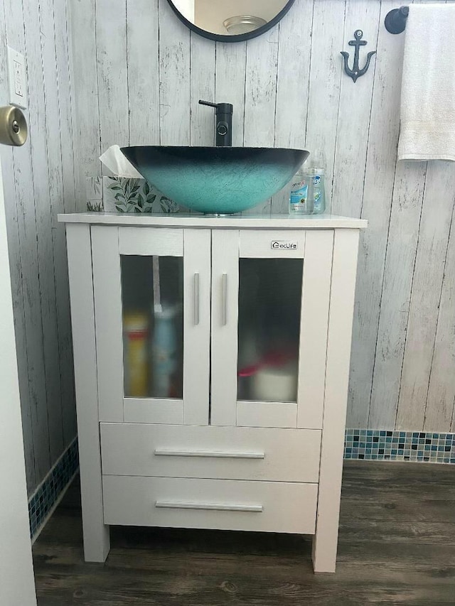 interior space featuring wood-type flooring, vanity, and wood walls