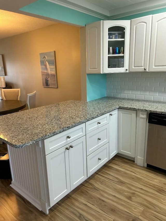 kitchen with dishwasher, decorative backsplash, kitchen peninsula, and white cabinetry