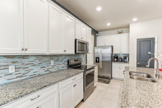 kitchen with white cabinets, sink, light stone countertops, light tile patterned floors, and stainless steel appliances