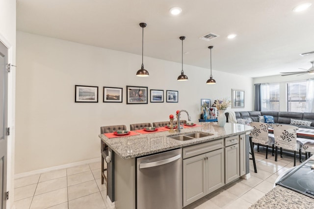 kitchen featuring sink, stainless steel dishwasher, light tile patterned floors, an island with sink, and a breakfast bar area