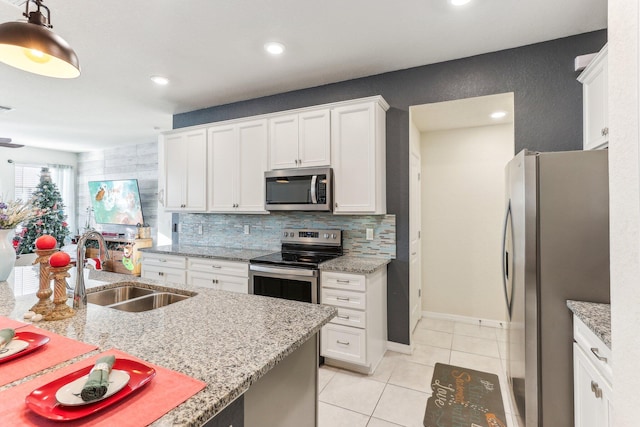 kitchen with tasteful backsplash, stainless steel appliances, sink, white cabinets, and hanging light fixtures