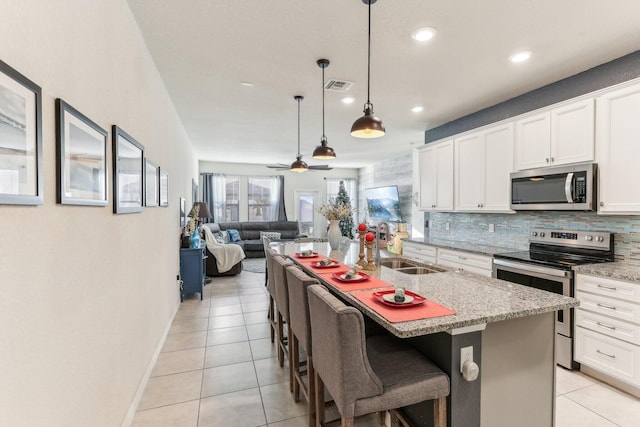 kitchen featuring white cabinetry, stainless steel appliances, a kitchen island with sink, and a breakfast bar area