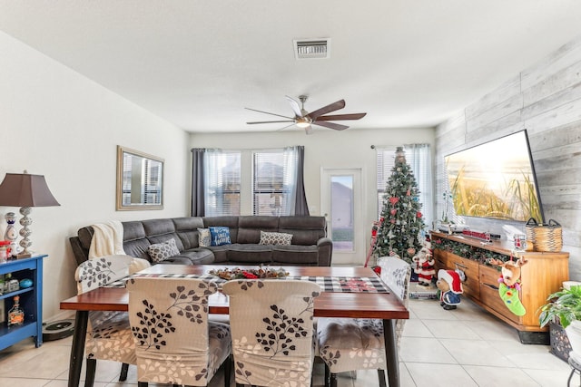 tiled living room with ceiling fan and wood walls