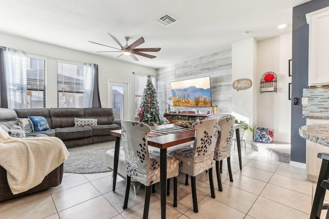 tiled dining area with ceiling fan and wooden walls