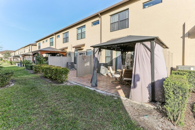 back of house featuring a gazebo, a yard, and central AC