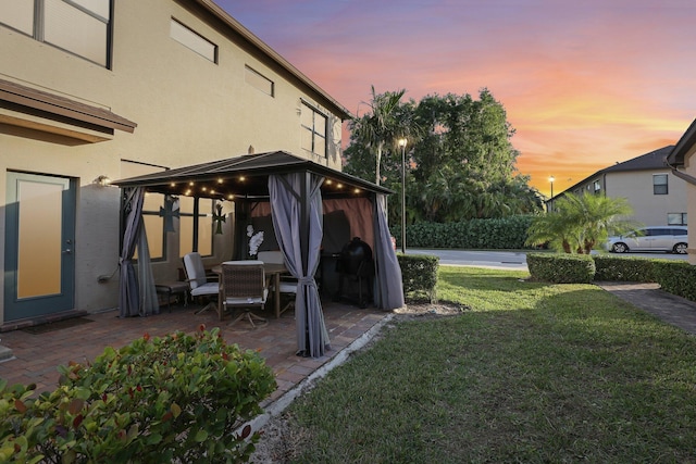 yard at dusk featuring a gazebo and a patio area