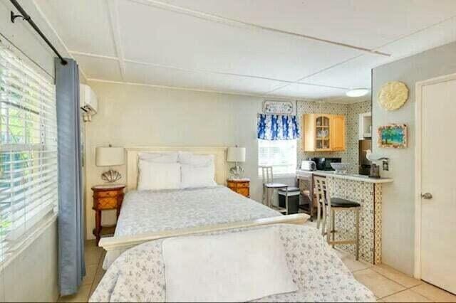 bedroom with an AC wall unit and light tile patterned flooring