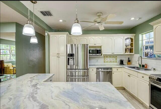 kitchen with decorative backsplash, sink, stainless steel appliances, and hanging light fixtures