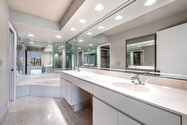 bathroom with vanity, a bath, and a textured ceiling