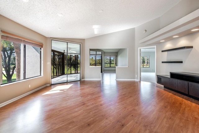 unfurnished living room with ceiling fan, vaulted ceiling, light hardwood / wood-style floors, and a textured ceiling