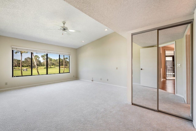 carpeted empty room with ceiling fan, lofted ceiling, and a textured ceiling