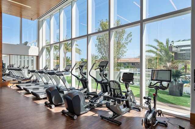 exercise room with a towering ceiling, hardwood / wood-style floors, expansive windows, and wood ceiling