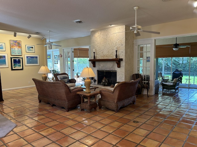 living room with ceiling fan, a fireplace, and tile patterned flooring